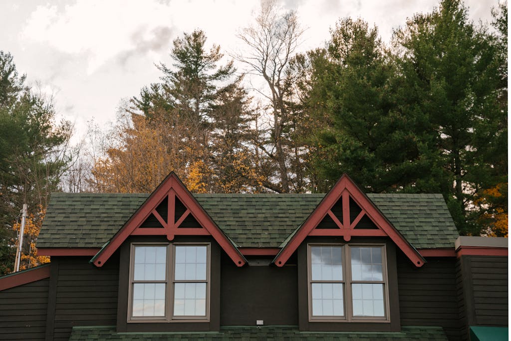 Facade of aged residential cottage located in autumn forest against cloudy sky